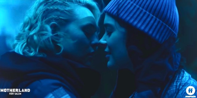 Two witches kissing against a cast of blue light