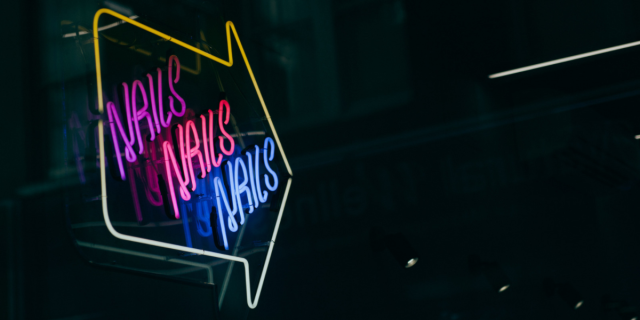 Image shows the words "Nails Nails Nails" inside of an arrow in the colors purple pink and blue