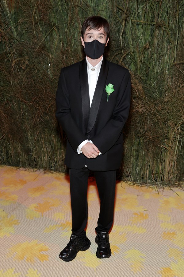 Elliott Page in a black tux and a green ribbon on his lapel, he is wearing a mask.