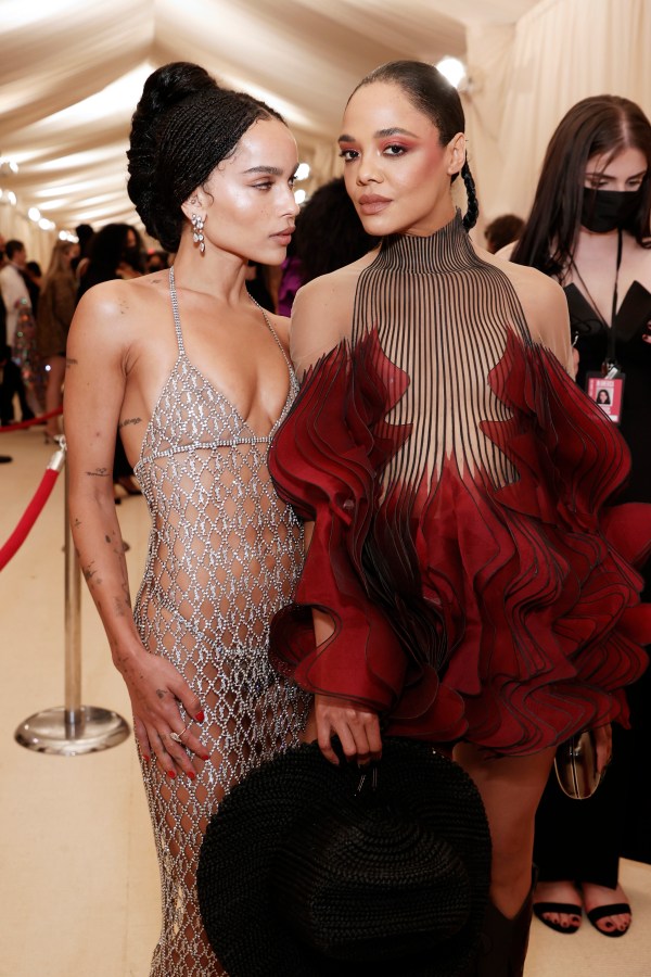 Zoe Kravitz in a see-throw chainlink gown and Tessa Thompson in a see through gown with deep red feathers on the bottom, both on the MET red carpet 2021