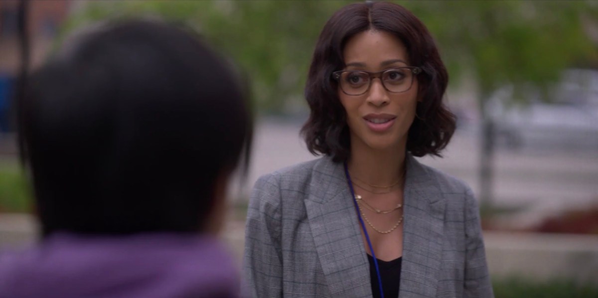 Claudia in a grey blazer outside the LGBT Center, talking to Micah