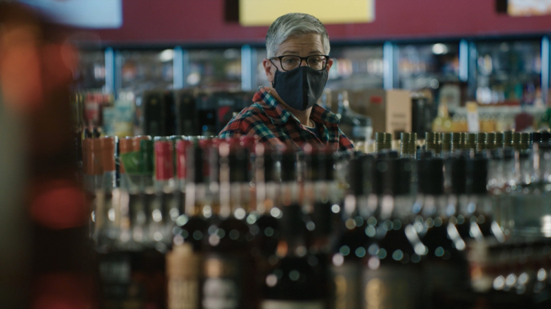 Abby stands in a liquor store with a mask on