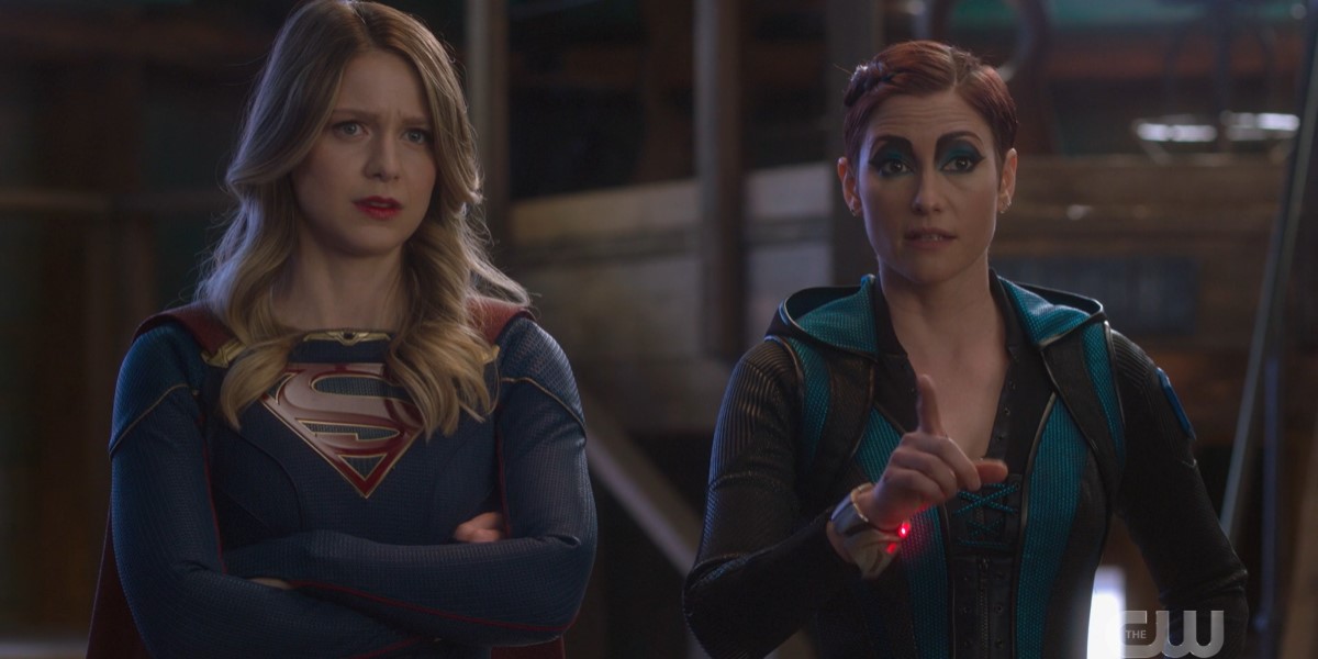 Supergirl 611: Kara with her arms crossed, Alex pointing a figure, both expressions look curious but a little concerned