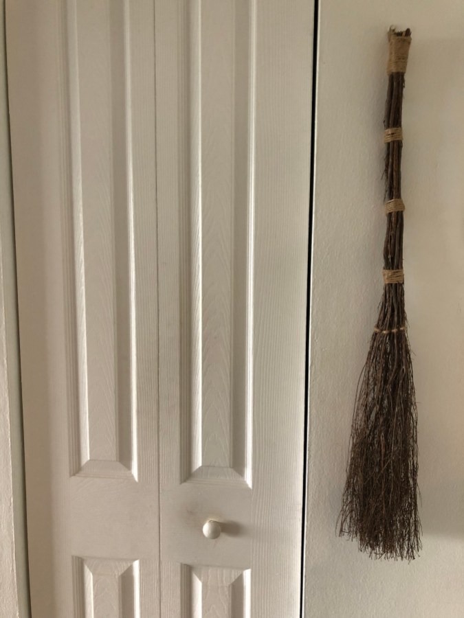 A cinnamon broom hanging next to a closet