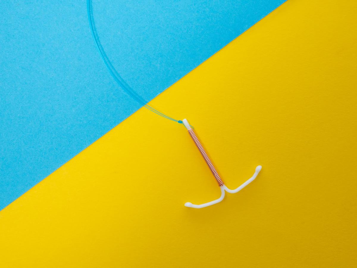 Image shows an IUD on a background of blue and yellow