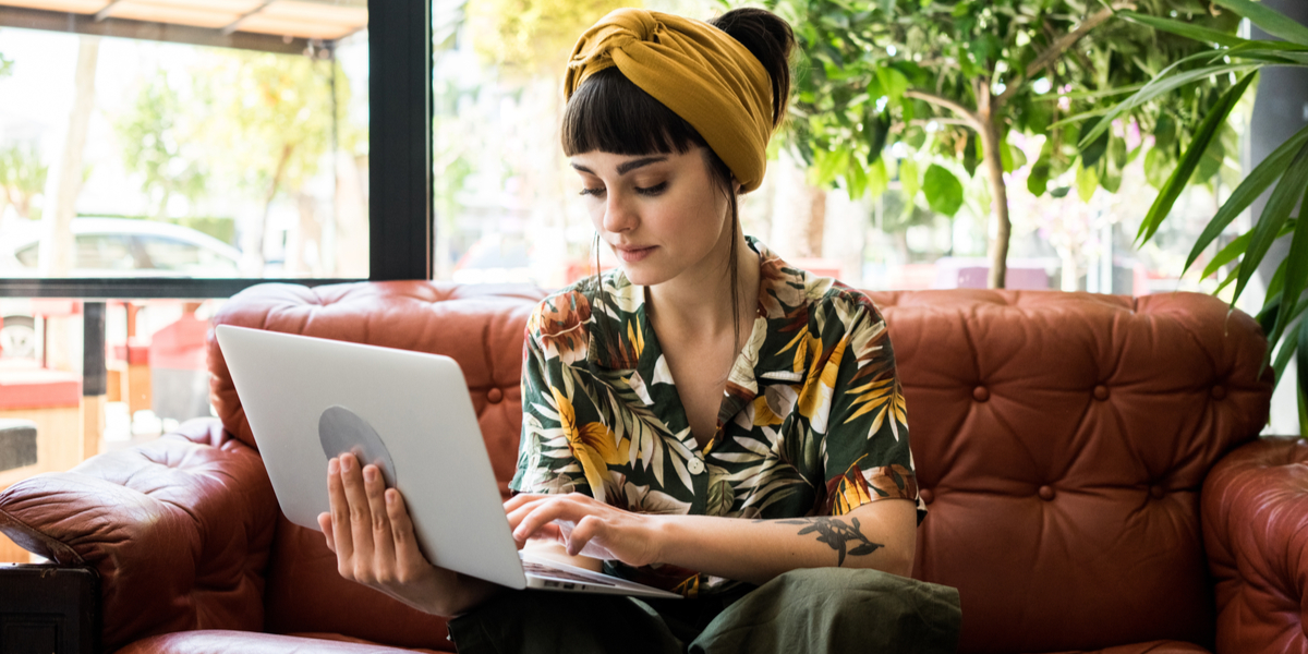 A brunette woman with a yellow hand band and a bright shirt works on a computer.