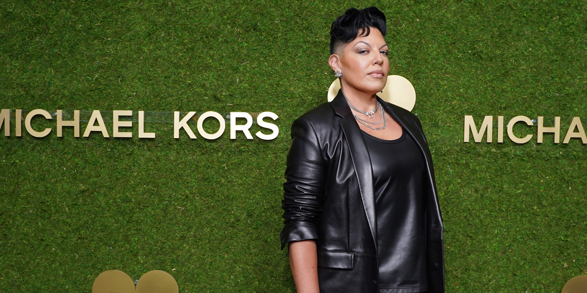 Sara Ramirez in a leather jacket against a green grass wall