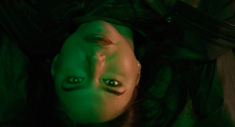 Sera-Lys McArthur lies back with her face lit up green