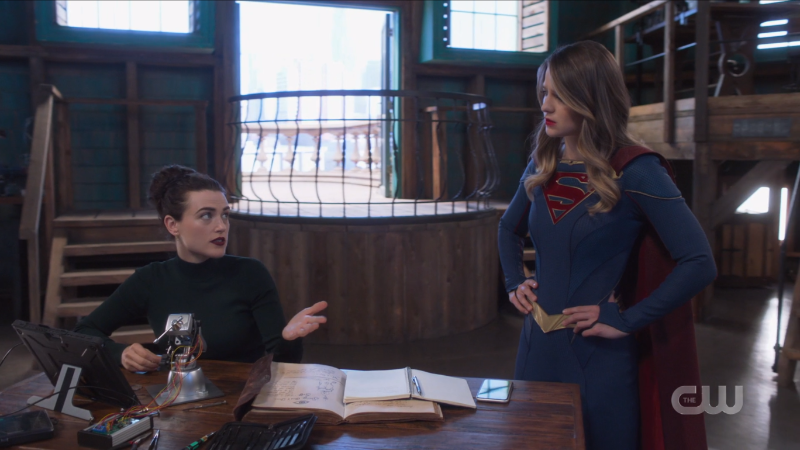Lena gestures while she explains something to Supergirl