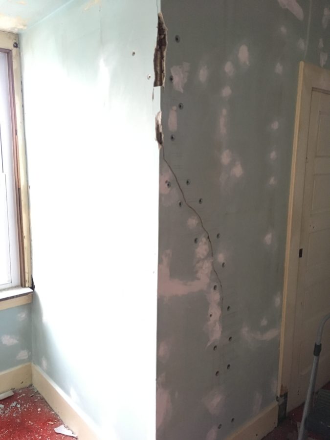 This is a photo of a corner in the same nook as above. It is also showing large chunks of plaster that have fallen off the lath. There are plaster washers installed up a crack in the wall. It is partially patched and repaired.