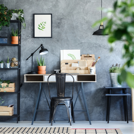 A minimalist desk setup with a small lamp and shelves of plants on either side