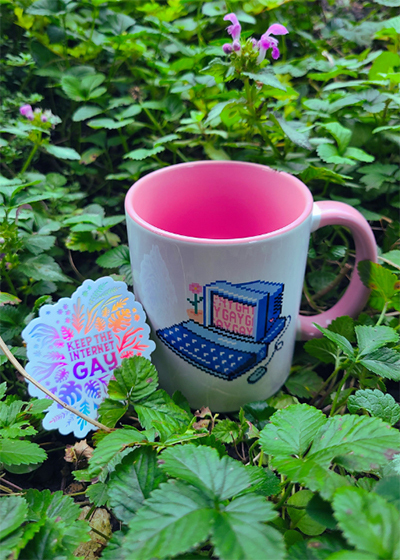 A photo of the Keep the Internet Gay holographic sticker and the Gay computer mug - both perks you can get as part of the fundraiser. Give a donation through our squarespace site to get a gift!