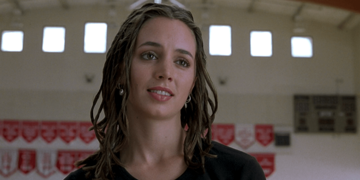 Image Shows Missy, a white woman with locs, standing in a gym with an attitudinal facial expression