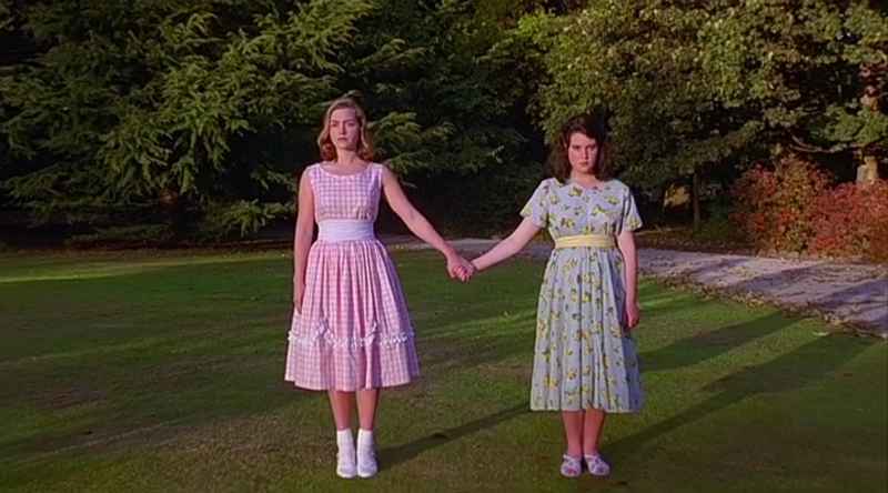 Kate Winslet and Melanie Lynskey hold hands wearing pink and blue pastel dresses