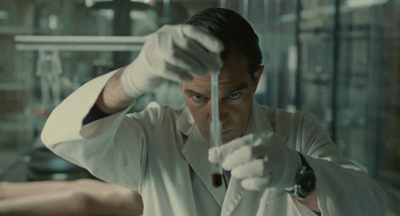 Antonio Banderas in a lab coat looks at a vial