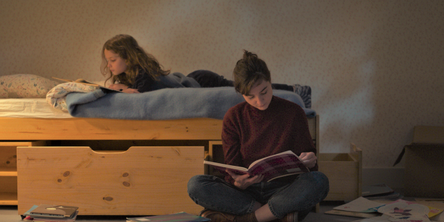 Petite Maman review: Joséphine Sanz as Nelly and Nina Meurisse as her mother read books together, Nelly on her bed, her mother on the floor next to her