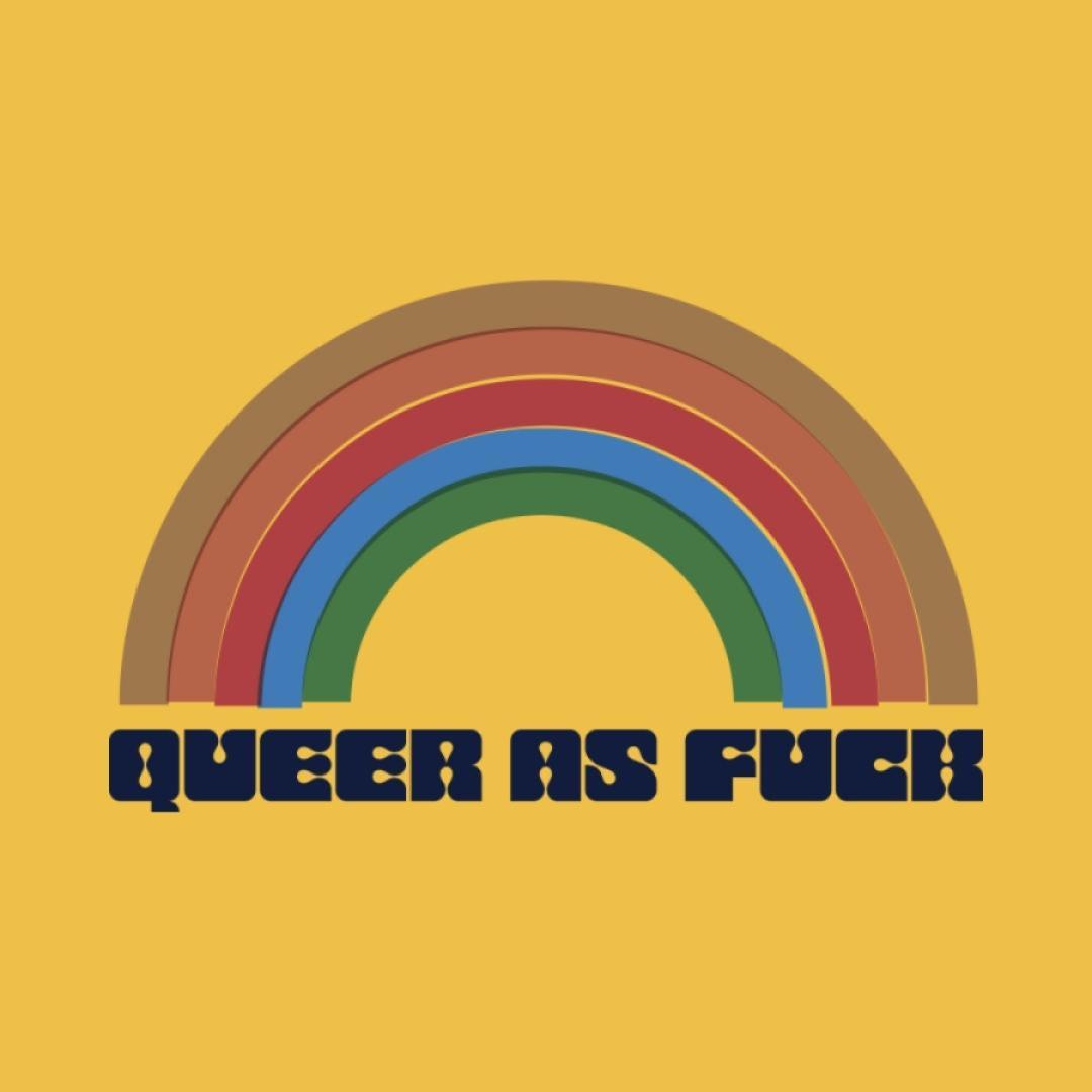 An offset rainbow in muted tones of brown, rust, red, blue and green with the words "QUEER AS FUCK" written in a 70's style block decorative font on a mustard yellow hoodie.