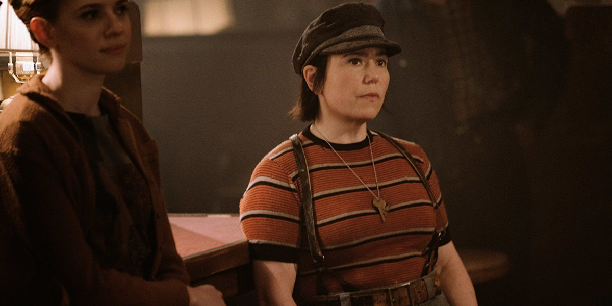 Image shows Susie Myerson, a white cis person, in a striped shirt, newsboy hat and suspenders. Her facial expression is one of slight concern and annoyance.