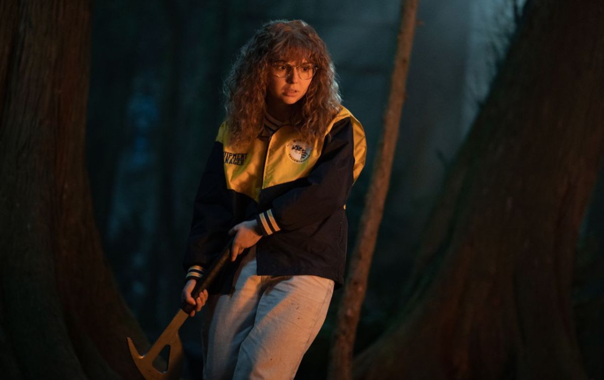 A screencap of Misty Quigley from the TV show Yellowjackets holding an axe in the woods
