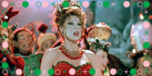 Christine Baranski from the live action version of The Grinch Who Stole Christmas stands in a low-cut, sleeveless top in a crowd of Whoville characters. Pink and green polka dots create a border around the image.