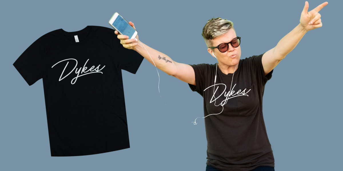 a older masc dyke holding up her arms wearing the DYKES tee