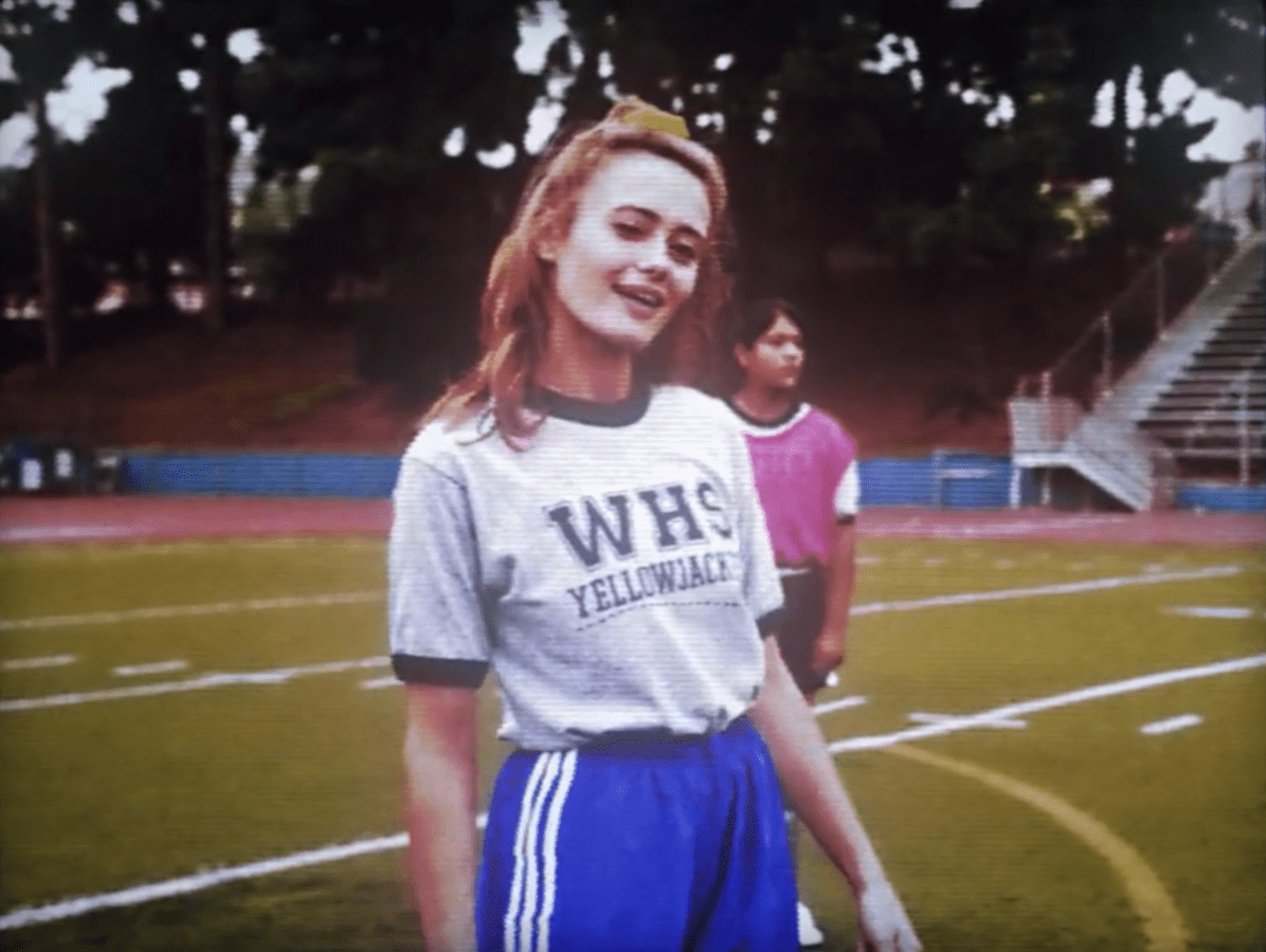 A screenshot of the opening title sequence for "Yellowjackets" featuring Jackie in her soccer uniform winking at the camera