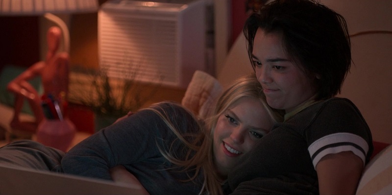 Alicia and Leighton snuggle next to each other and watch reality dating shows on Alicia's laptop.