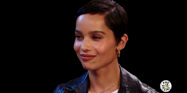 Zoë Kravitz in a leather jacket, red lip, and small gold earrings