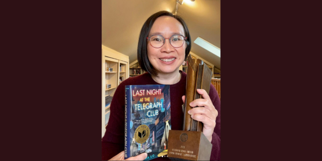 Malinda Lo holding her book Last Night At The Telegraph Club and her National Book Award trophy