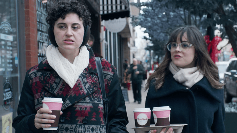 Emma and Charlyne walk down the street with coffee