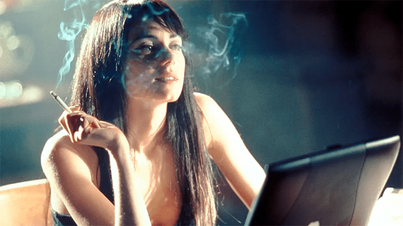 Jenny sits at a computer smoking