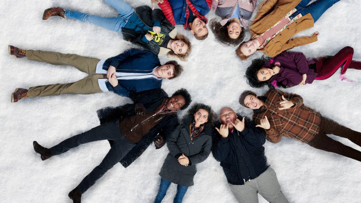 cast of "Let it Snow" lying on the snow in a pinweheel