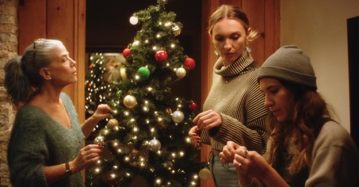 Two white women and one of their mothers decorating a Christmas tree