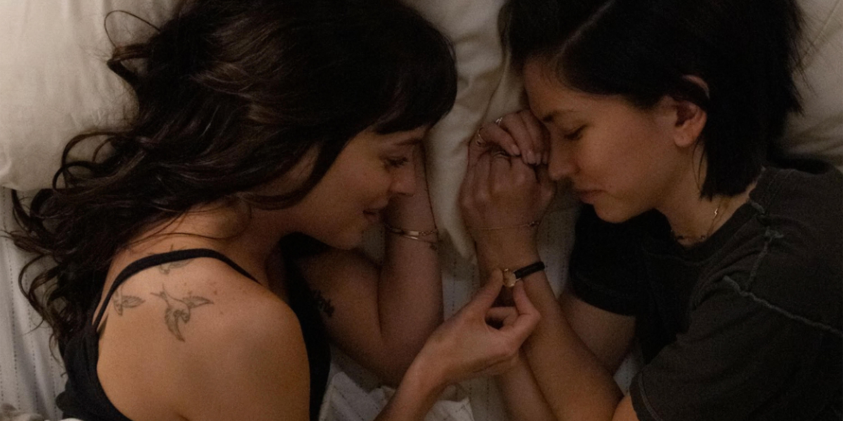 Dakota Johnson and Sonoya Mizuno lie in bed next to each other.