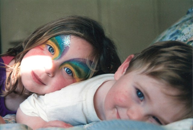 Two children, a girl and a boy, smile while snuggling.