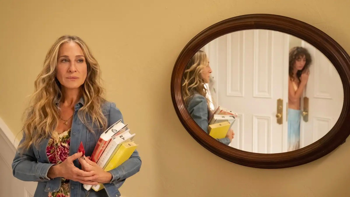 Carrie stands in front of a mirror that her neighbor is also looking into