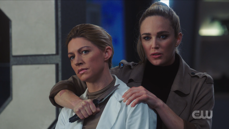 Android Sara holds Dr. Sharpe at knifepoint