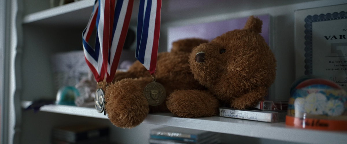 A photo of a teddy bear missing an eye on a shelf with soccer medals from the "Yellowjackets" pilot