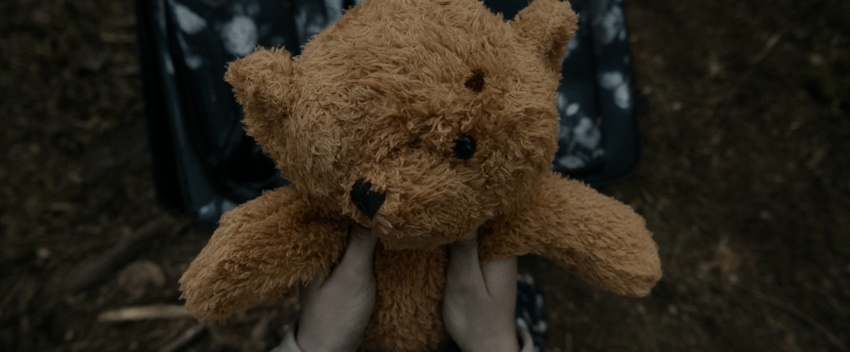 Hands holding a teddy bear missing an eye from the "Yellowjackets" episode "F Sharp"