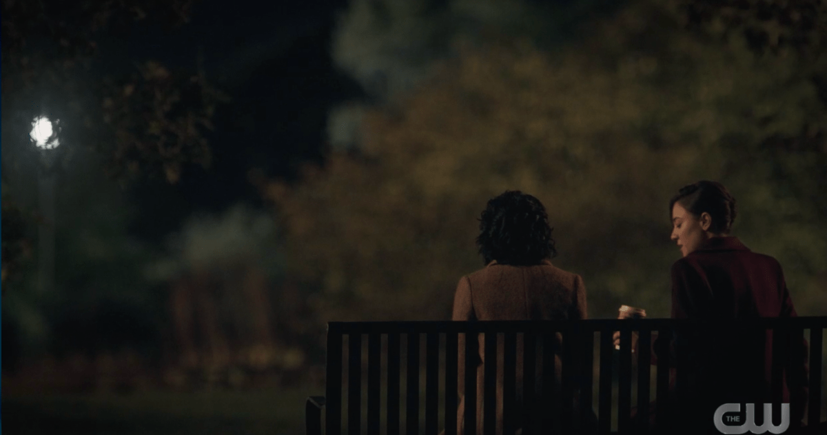 Soraya and Jessica sit on a park bench at night exchanging secret messages.
