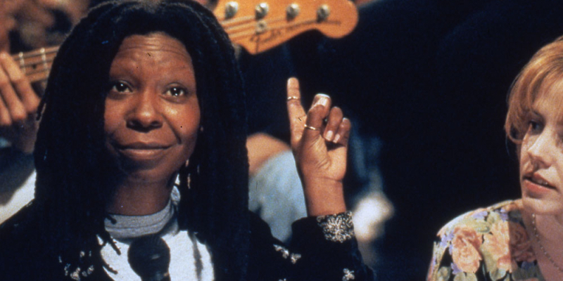 Whoopi Goldberg holds a finger up on stage as Mary-Louise Parker looks at her.