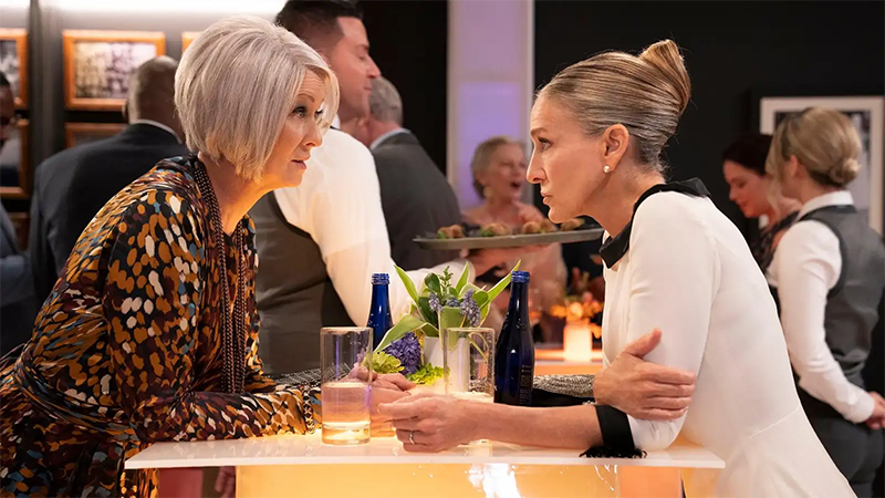 Carrie and Miranda lean toward each other over a dinner table