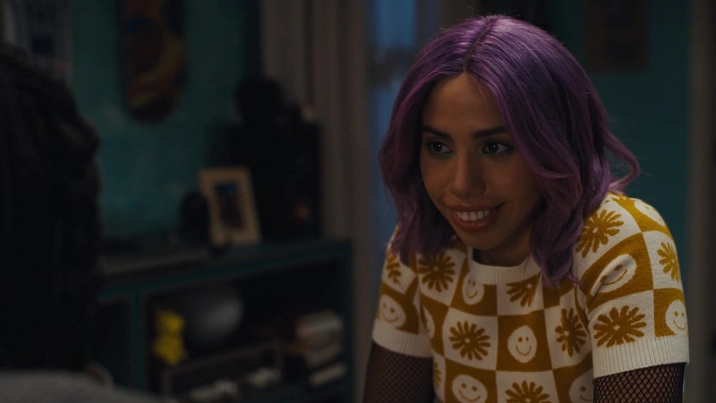Lourdes, with her trademark purple hair, sits on the edge of Naomi's bed and recalls the details from a Zantanna comic.