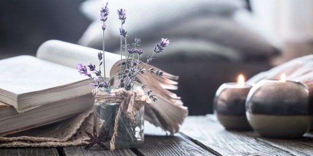 An open book and a vase of wildflowers sits on a rustic table