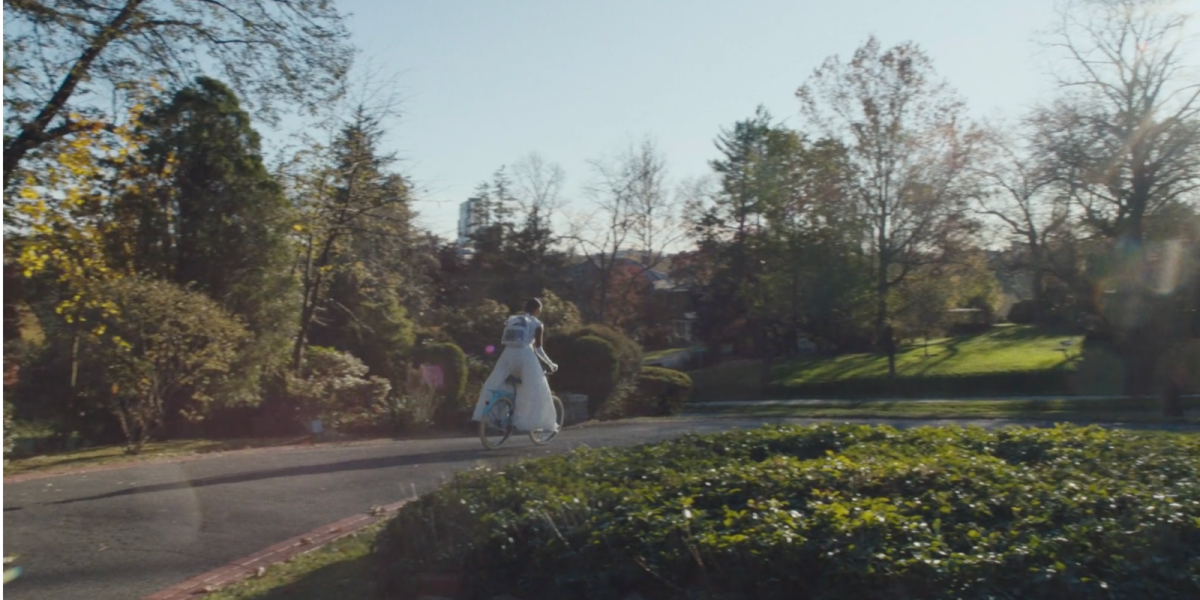 Celeste rides her bike away from her home while wearing her white cotillion dress.