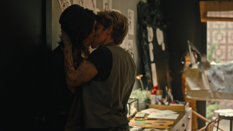 Greta kisses Katherine forcefully against the wall in the tattoo parlor's office.