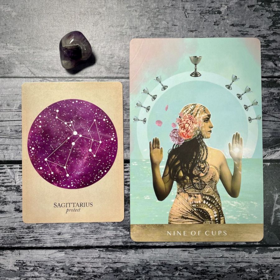 A card says sagittarius: protect with a purple circle, next to a card that says nine of cups with an illustration of women in a gold dress with her hands up