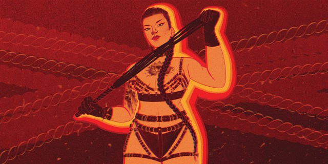 An Asian woman stand against a red background, wearing a leather, strappy lingerie / harness situation. She holds a leather flogger that she stretches out between her gloved hands while eyeing the viewer. She has a chest tattoo and wears her hair in a long, single braid that winds down her front.
