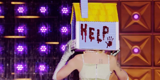 drag race recap 1405: The back of Willow Pill's head on the runway. She holds onto her house headpiece that says HELP on the back with a bloody handprint