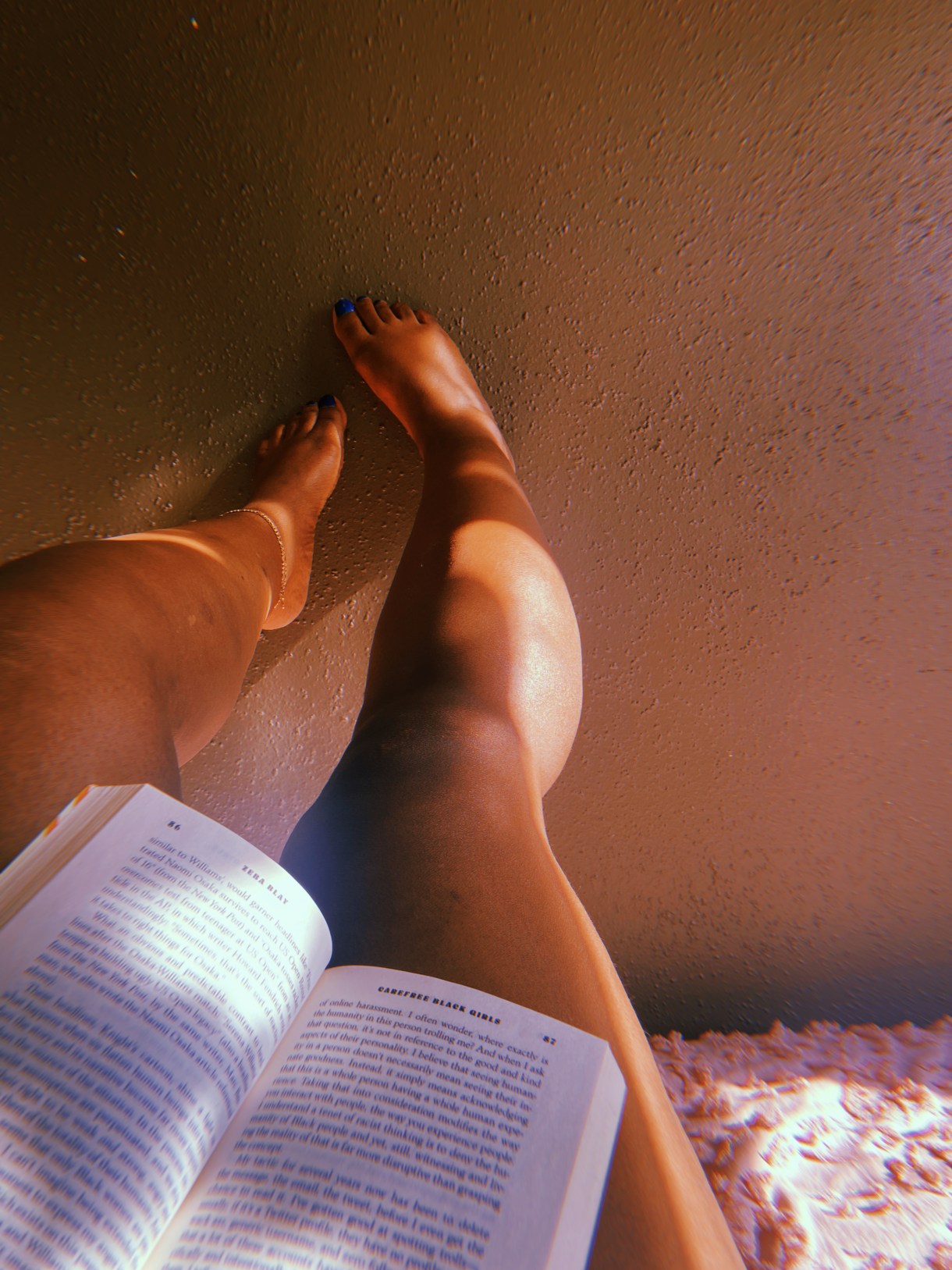This is a photo taken from Shelli's perspective while reading a book. All you can see is the open book, her legs and feet with blue nail polish on the toes!